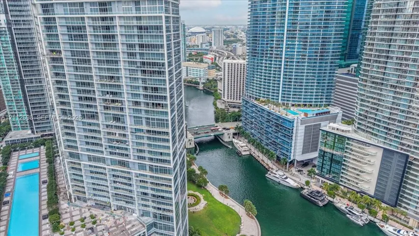 High-rise residential tower featuring floor-to-ceiling glass windows, private balconies, and proximity to a waterway with boat slips and a swimming pool