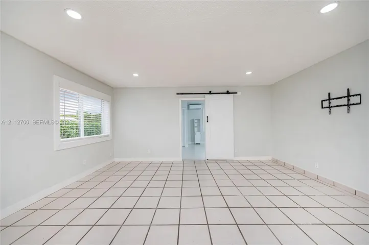 Interior space featuring ceramic tile flooring, recessed lighting, a sliding barn-style door, and a dual-pane window with white trim