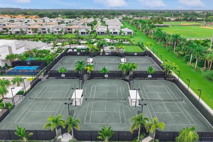 Multi-court facility featuring hard-surface tennis courts, dedicated pickleball court, and outdoor lighting fixtures