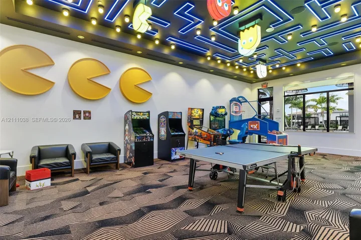 Recreation area featuring custom recessed ceiling lighting, decorative wall-mounted installations, geometric pattern carpeting, and large-format windowpane