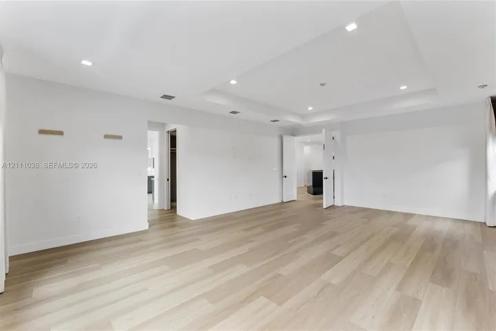 Interior space featuring a recessed tray ceiling, wood-finish flooring, and integrated recessed lighting