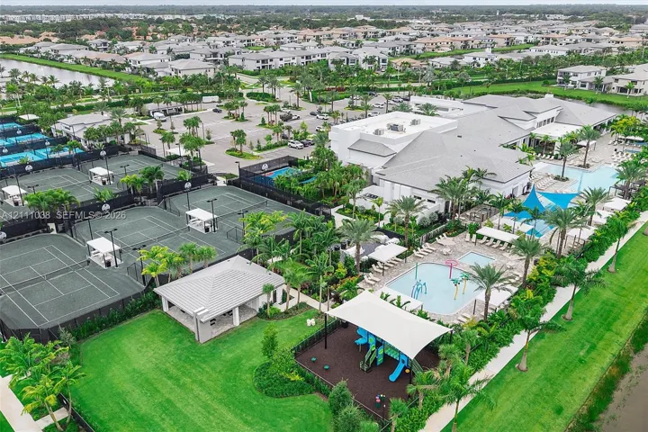 Community recreational complex featuring multiple tennis courts, a swimming pool with water features, a playground with shade structures, and an expansive clubhouse