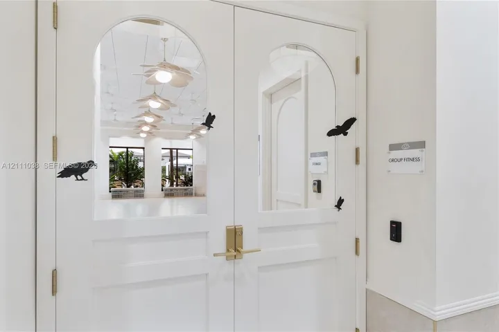 Double doors featuring arched glass panels, brass-finish lever hardware, and electronic keycard access entry