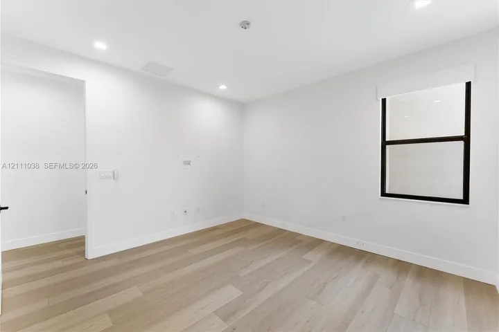 Neutral interior featuring wood-finish flooring, recessed lighting, and a window with a dark-finished frame