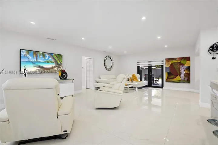 Open-concept interior featuring large-format tile flooring, recessed lighting, and glass-paned double doors