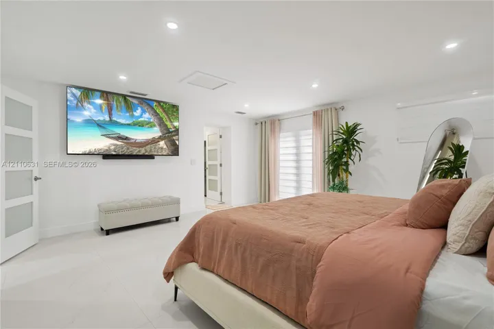 Neutral interior featuring large-format light-toned tile flooring, recessed ceiling lighting, and multiple solid-core doors with frosted glass inserts