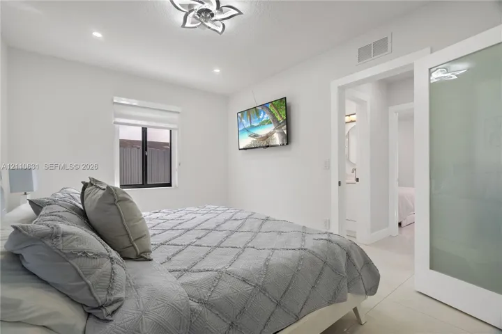 Frosted glass sliding door, recessed ceiling lighting, decorative floral-motif ceiling fixture, neutral tile flooring, and clean-lined interior trim