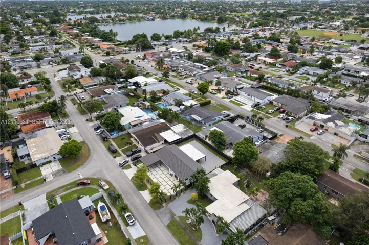 Aerial perspective featuring a residential property with a multi-vehicle driveway, concrete grid patio, and proximity to a large inland lake