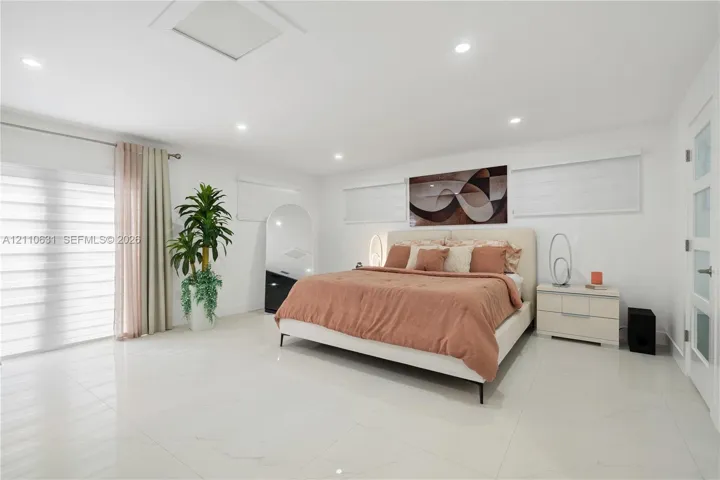 Large-format tile flooring, recessed ceiling lighting, glass sliding door, and multi-panel interior door