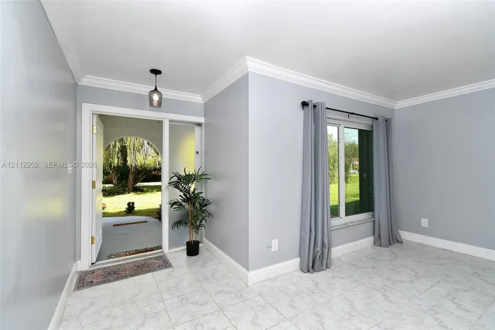 Foyer featuring tile flooring, crown molding, and a decorative pendant light