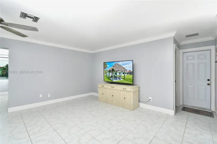 Interior space featuring light-toned tile flooring, crown molding, and a ceiling fan with integrated lighting