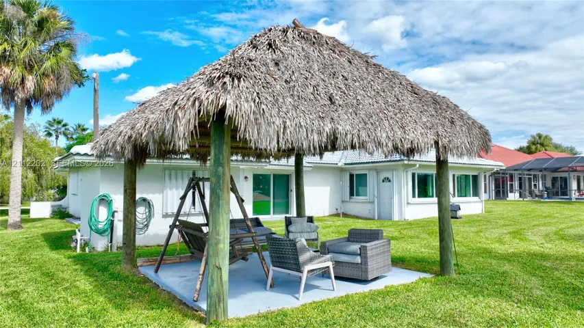 Outdoor pavilion featuring a thatched roof, timber support posts, and a concrete patio floor
