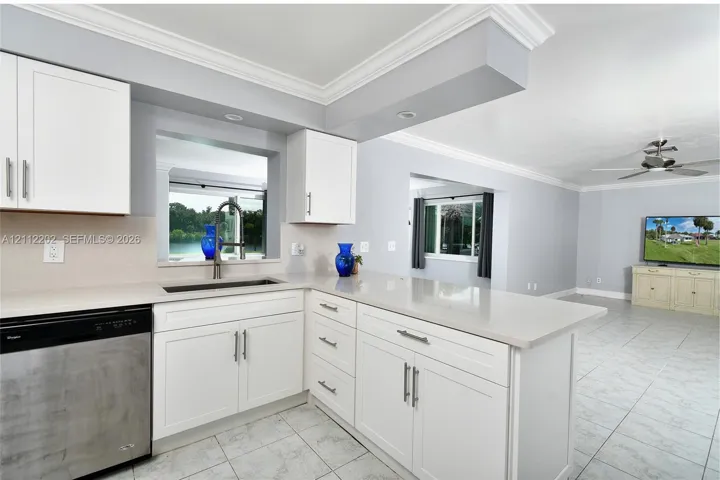 Kitchen featuring white shaker-style cabinetry, quartz countertops, stainless steel undermount sink, and recessed lighting, finished with ceramic tile flooring