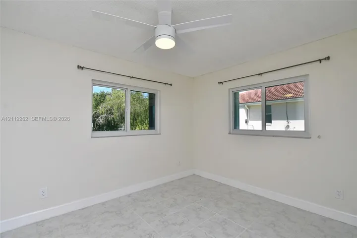 Room featuring neutral wall paint, tile flooring, and a ceiling-mounted light fixture with a fan