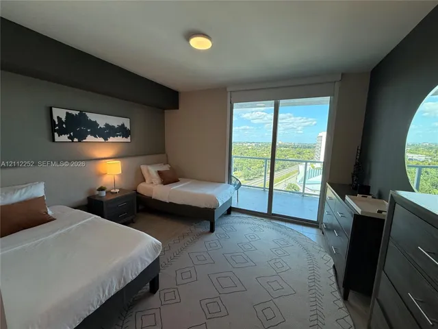 Sliding glass doors opening to a private balcony, large circular window, and neutral wall-finish flooring