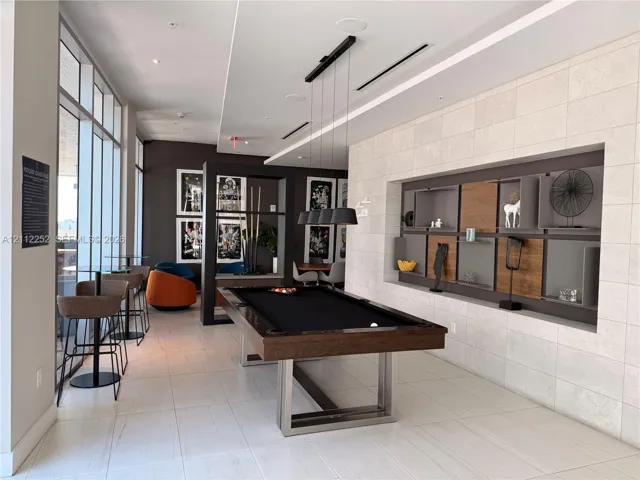 Large-format tiled flooring, recessed wall shelving with integrated wood-panel inserts, floor-to-ceiling windows, and contemporary pendant lighting