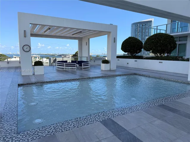 Terrace featuring a swimming pool with decorative mosaic tile trim, a structural pergola, large-format tile flooring, and integrated wall lighting