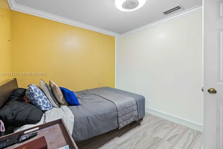 Room featuring wood-finish tile flooring, crown molding, and a central flush-mount ceiling fixture