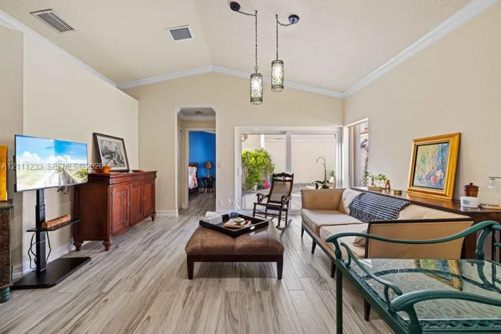 Vaulted ceilings featuring decorative pendant lighting, sliding glass doors, and wood-finish flooring