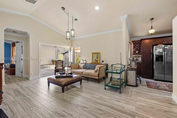 Vaulted ceilings with recessed lighting, wood-finish tile flooring, sliding glass doors, and dark wood cabinetry with built-in wine storage