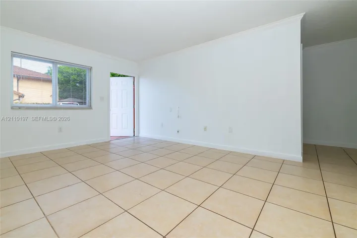 Neutral-toned tile flooring, white wall finishes, crown molding, and a single-pane horizontal window