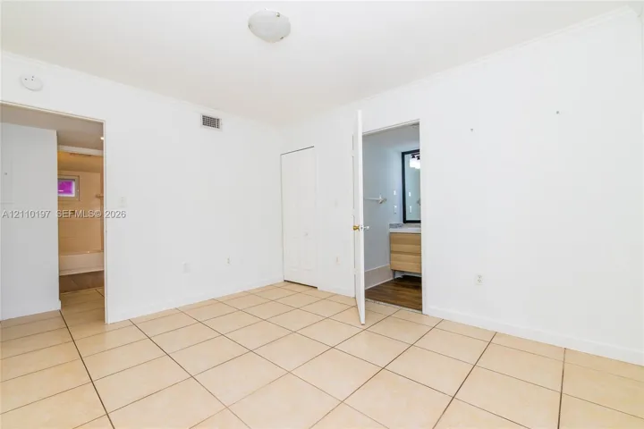 Interior space featuring ceramic tile flooring, crown molding, a flush-mount ceiling light fixture, and a reach-in closet with double-panel doors