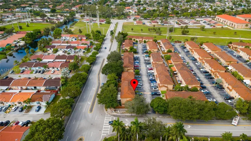 Aerial perspective featuring a multi-unit residential complex with tile roofing, mature landscaping, and dedicated parking areas