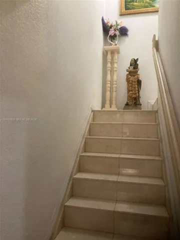 Staircase featuring stone-finish treads and a neutral-toned handrail