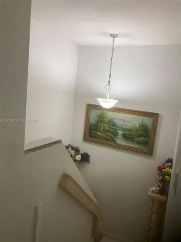 Neutral wall color, wooden handrail, and pendant light fixture