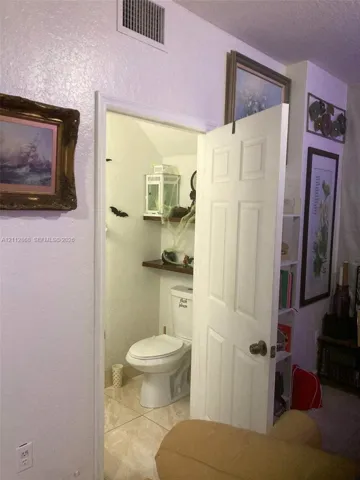 Bathroom featuring a six-panel door, stone-tile flooring, and built-in wall shelving
