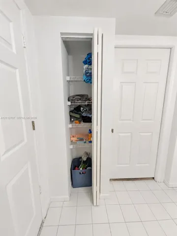Built-in closet featuring white bi-fold doors, grid-pattern wire shelving, and tiled flooring