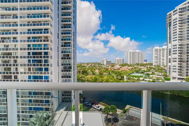 Balcony with glass panel railing overlooking a waterway and urban skyline