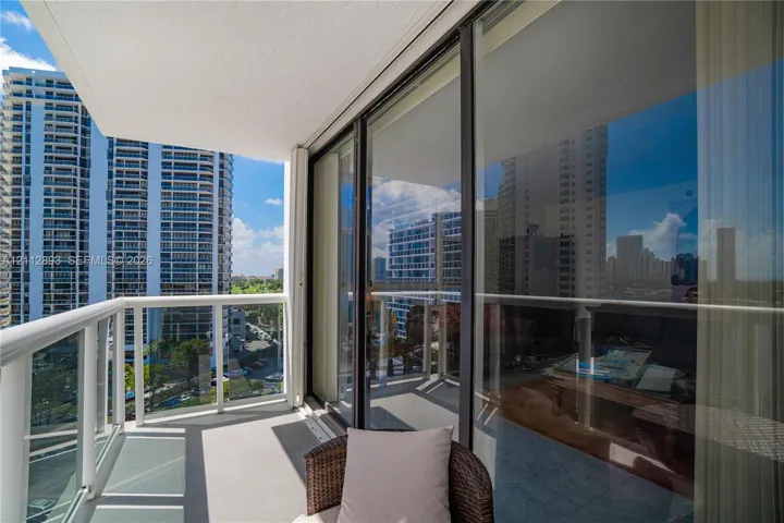 Private balcony featuring a glass-panel railing, smooth concrete flooring, and full-height sliding glass doors