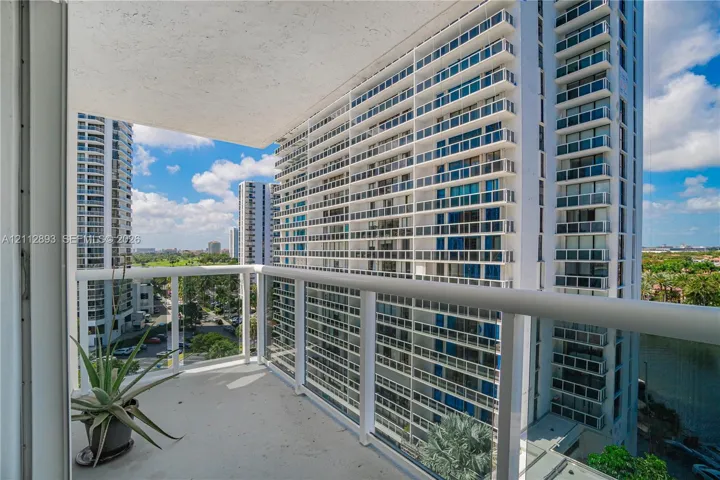 Covered balcony featuring concrete flooring and a white powder-coated metal railing with glass panels