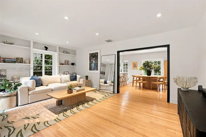 Living area featuring wood-finish flooring, recessed lighting, and expansive floor-to-ceiling built-in shelving