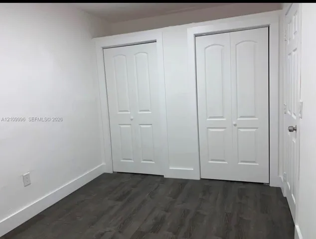 Wood-finish flooring, two sets of white paneled closet doors, and solid-core interior doors