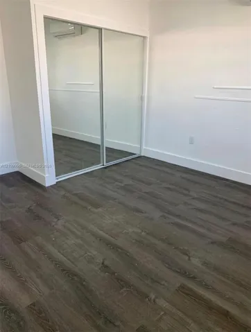 Wood-finish flooring, sliding mirrored closet doors, and wall-mounted climate control unit