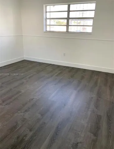 Interior space featuring wood-finish flooring, white walls with chair rail molding, and a multi-pane horizontal window