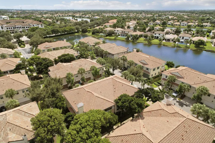 Aerial perspective of residential community featuring tiled roofs, mature trees, and waterfront lots