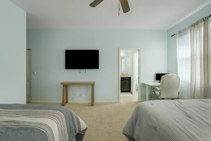 Neutral-toned carpeted flooring, ceiling fan with light fixture, and windows with drapery hardware