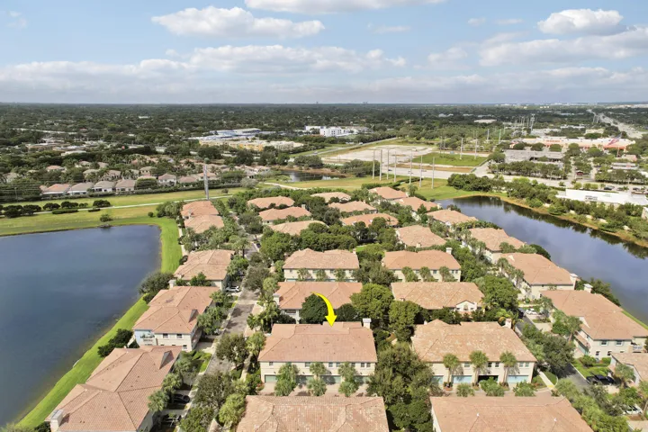 Aerial perspective of multi-family residences featuring clay tile roofs, textured stucco exteriors, and surrounding waterfront scenery