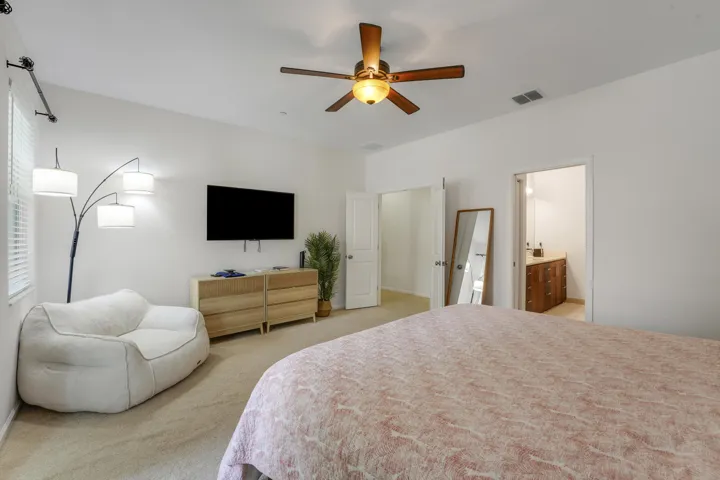 Neutral-toned room featuring carpeted flooring, a ceiling fan with integrated lighting, and multiple interior doors