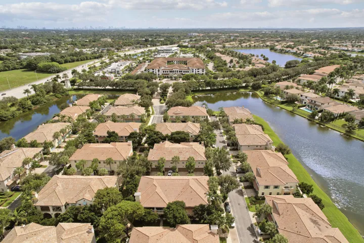 Aerial perspective of residential community featuring tile roofs, mature landscaping, and waterfront surroundings