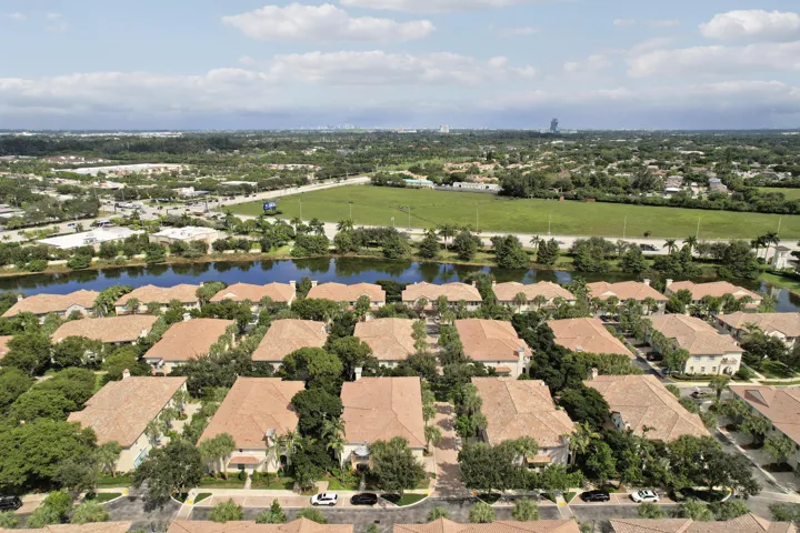 Aerial perspective featuring tile roofing, mature landscaping, and proximity to a water feature
