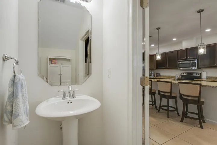 Powder room featuring a pedestal sink, polished chrome faucet, and beveled-edge mirror