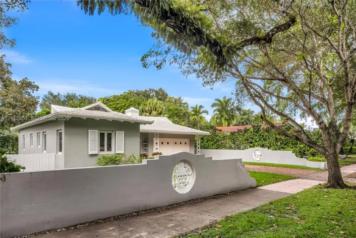 Single-story residence featuring a low-slope roof, white exterior shutters, and a decorative concrete perimeter wall with circular lattice detailing