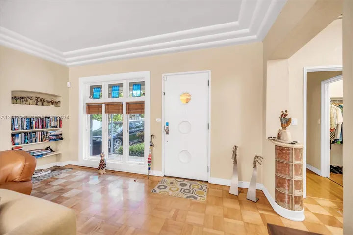 Parquet flooring, tiered crown molding, built-in shelving, stained glass window accents, and a curved glass block pedestal