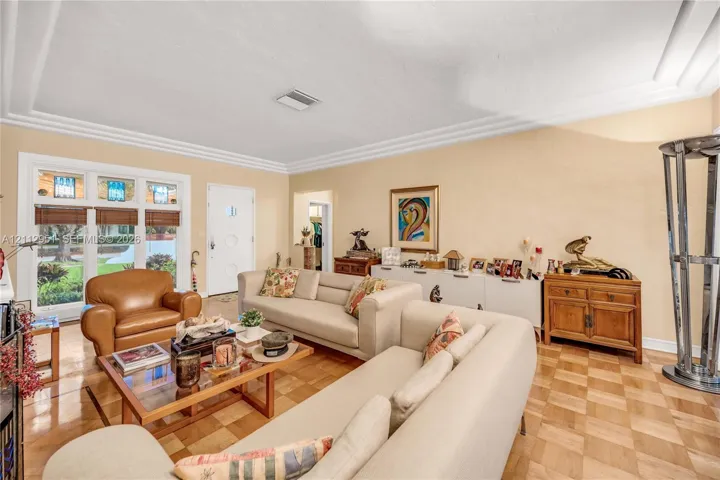 Parquet wood-finish flooring, multi-pane window with integrated stained glass detailing, stepped crown molding, and a solid-core entry door with circular decorative glass inlay