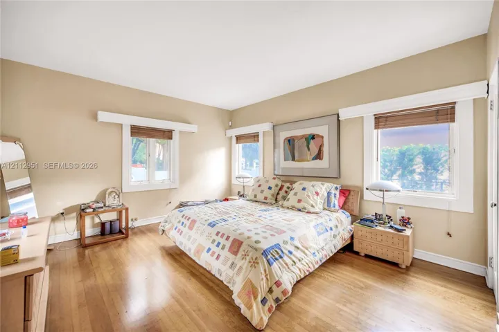 Wood-finish flooring, neutral wall color, and multiple windows with white trim and headers