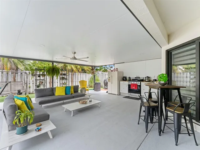 Covered patio featuring a painted concrete floor, ceiling fan, recessed lighting, and an outdoor kitchenette with white cabinetry